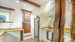 A kitchen with a wooden door, a sink, and a countertop with fruits. - 2 Bed in Lindale (oc-c34128) (Lindale)