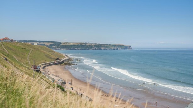 A coastal landscape with a beach, cliffs, and a train track. - 2 Bed in Whitby (oc-w1028) (Whitby)