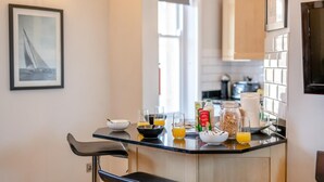 A modern kitchen with a glass island, seating area, and a framed picture on the wall. - 2 Bed in Whitby (oc-w1028) (Whitby)