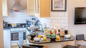 A modern kitchen with a central island, microwave, and stove. There are various food items and a framed picture on the wall. - 2 Bed in Whitby (oc-w1028) (Whitby)