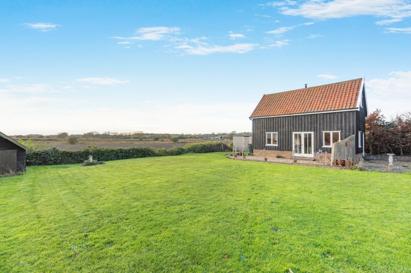 Une maison de plain-pied avec un toit en tuiles et une pelouse bien entretenue à l’avant.