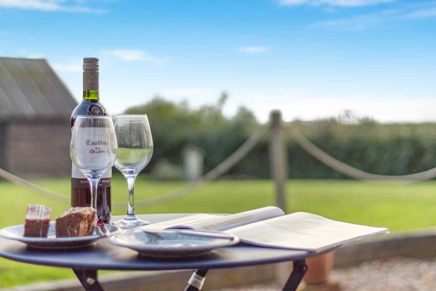 Une table avec une bouteille de vin Casillero del Diablo, deux verres et une assiette contenant des aliments.