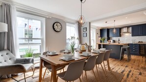 A modern dining room with a wooden table, grey chairs, and a clock on the wall. - 2 Bed in St. Ives (oc-upper4) (St Ives)
