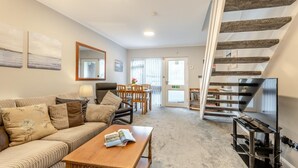A modern living room with a sofa, coffee table, and a staircase with a TV on the landing. - 2 Bed in Grasmere (oc-ld175) (Grasmere)