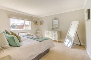 Un dormitorio con cama, cómoda, espejo y ventana.