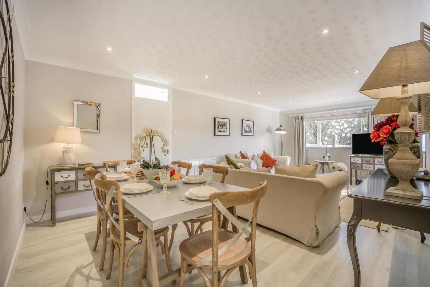 A modern living room with a dining area, a sofa, a TV, and a decorative vase.