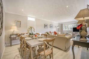 Una sala de estar moderna con comedor, un sofá, un televisor y un jarrón decorativo.