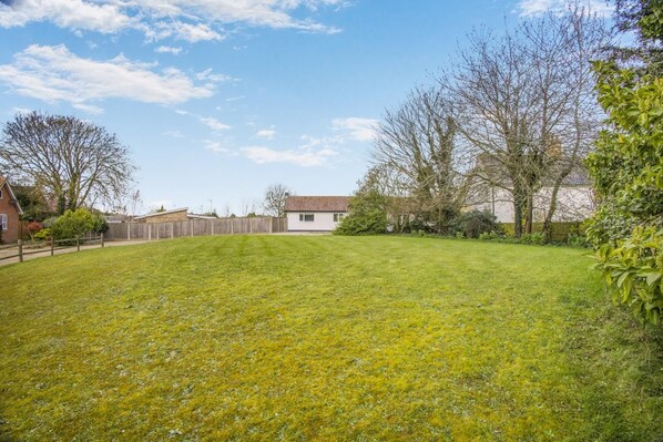 A residential backyard with a lawn, a wooden fence, and a house in the background.