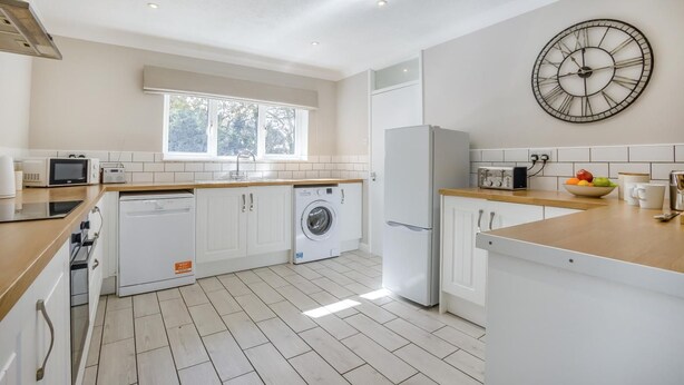 A modern kitchen with white cabinetry, a washing machine, a refrigerator, and a clock on the wall. - 2 Bed in Halesworth (oc-dak) (Halesworth)