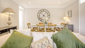 A dining area with a round table, chairs, a clock, and a lamp. - 2 Bed in Halesworth (oc-dak) (Halesworth)