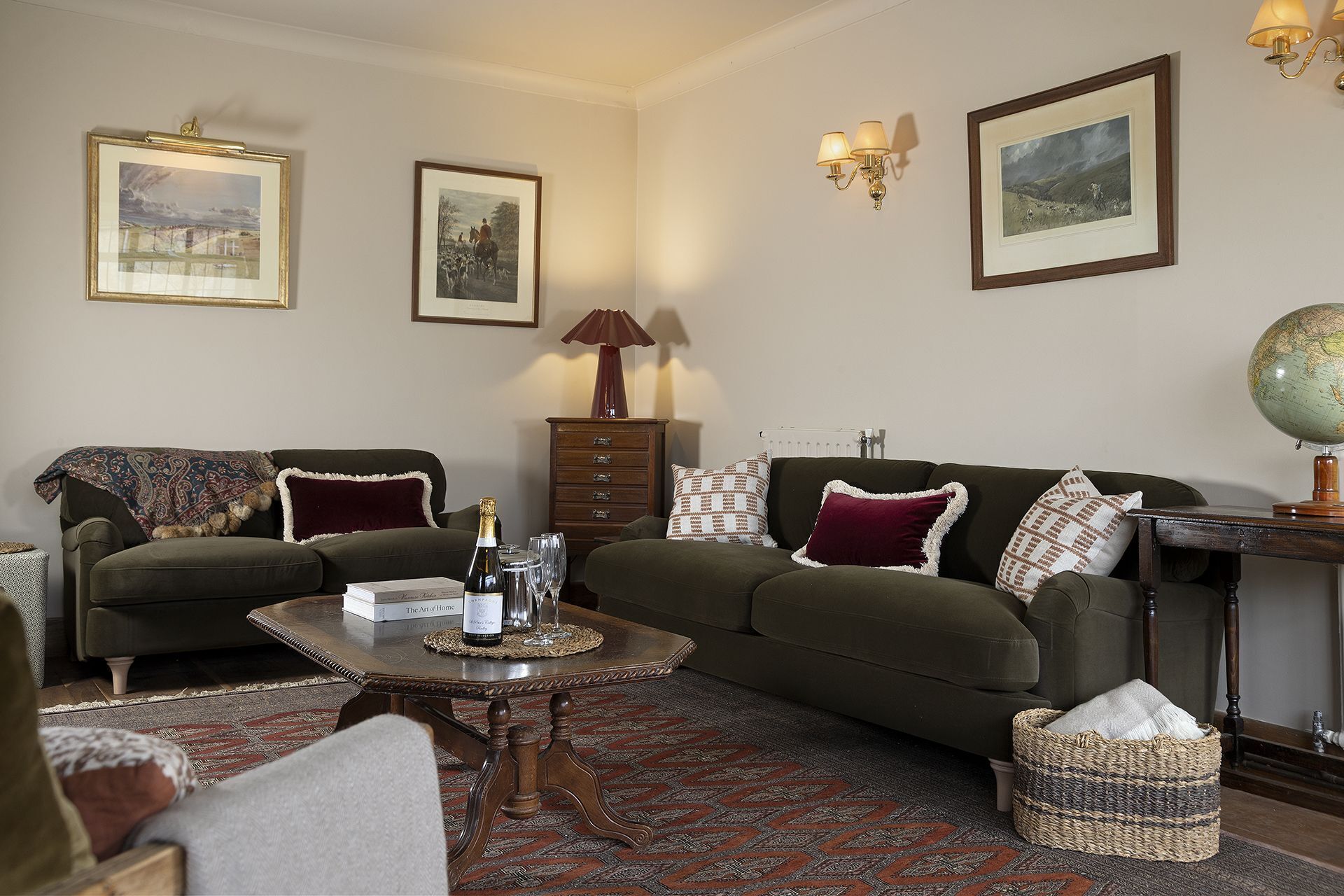 A cozy living room with a green sofa, a coffee table with a bottle of champagne, and a globe on a side table.