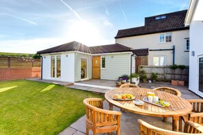 A residential property with a patio area, a dining table with chairs, and a small garden. - 4 Bed in Sheringham (oc-2330) (Sheringham)