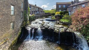Een stenen gebouw met een waterval, een smalle waterloop en een rij huizen.