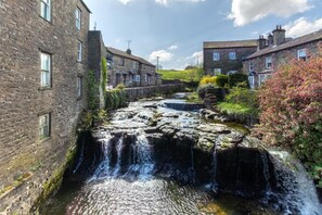 Ein Steinhaus mit einem Wasserfall, einem schmalen Wasserlauf und einer Reihe von Häusern.
