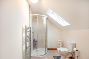 A modern bathroom with a glass shower enclosure, a toilet, and a skylight. - 3 Bed in Chapel St. Leonards (oc-r34145) (Chapel Saint Leonards)