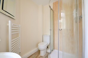 Een badkamer met toilet, een douchecabine van glas en een witte radiator.