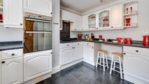 A modern kitchen with white cabinetry, a built-in oven, a microwave, and a coffee station. - 3 Bed in Cromer (oc-2256) (Cromer)