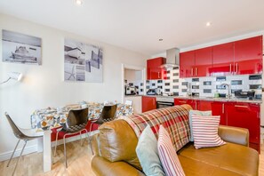 A modern kitchen with red cabinets and a dining area with a table and chairs.