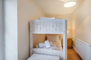 Ein Stockbett mit Holzbettrahmen, ein Nachttisch und eine Lampe.