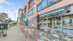 A street with outdoor seating, a cafe, and a building with a sign for 'Bradley's'. - 1 Bed in Penzance (oc-u34132) (Penzance)