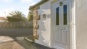 A building with a white exterior, a stone column, and a white door with a window. - 1 Bed in Penzance (oc-u34132) (Penzance)