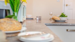 A kitchen counter with a loaf of bread, a bowl, a glass of water, and a small plant. - 1 Bed in St. Merryn (oc-p00645) (Saint Merryn)
