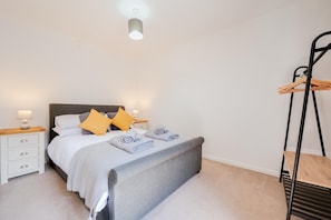 A bedroom with a bed, bedside tables, a hanging chair, and a ceiling light. - 1 Bed in Saundersfoot (oc-pw9269) (Saundersfoot)