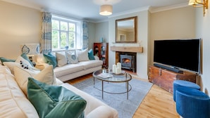 A living room with a sofa, a coffee table, a fireplace, and a television. - 4 Bed in Northrepps (oc-2332) (Northrepps)