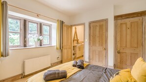 Ein Schlafzimmer mit einem Bett, einem Heizkörper, einem Fenster mit Vorhängen und Holztüren.