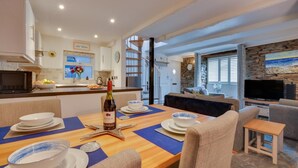 Una cocina moderna con comedor, una sala de estar con televisor y una pared de piedra.