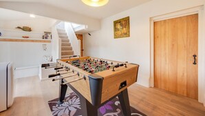 Ein gemütliches Zimmer mit einem Kicker, einer Treppe und einer Holztür.