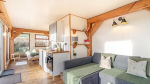 Et hyggeligt sommerhusindretning med tekøkken, en sofa og et spiseområde.