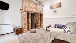 Una habitación acogedora con chimenea de ladrillo, un sofá cómodo y un televisor de pantalla plana montado en la pared.