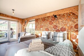 A bedroom with a stone wall, a bed, a sofa, and a view through a glass door. - 1 Bed in Newton In Bowland (oc-h34064) (Newton)