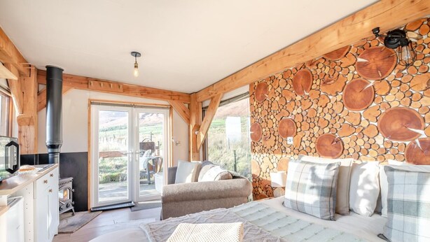 A cozy room with a bed, a wooden wall, a fireplace, and a view through a glass door. - 1 Bed in Newton In Bowland (oc-h34064) (Newton)