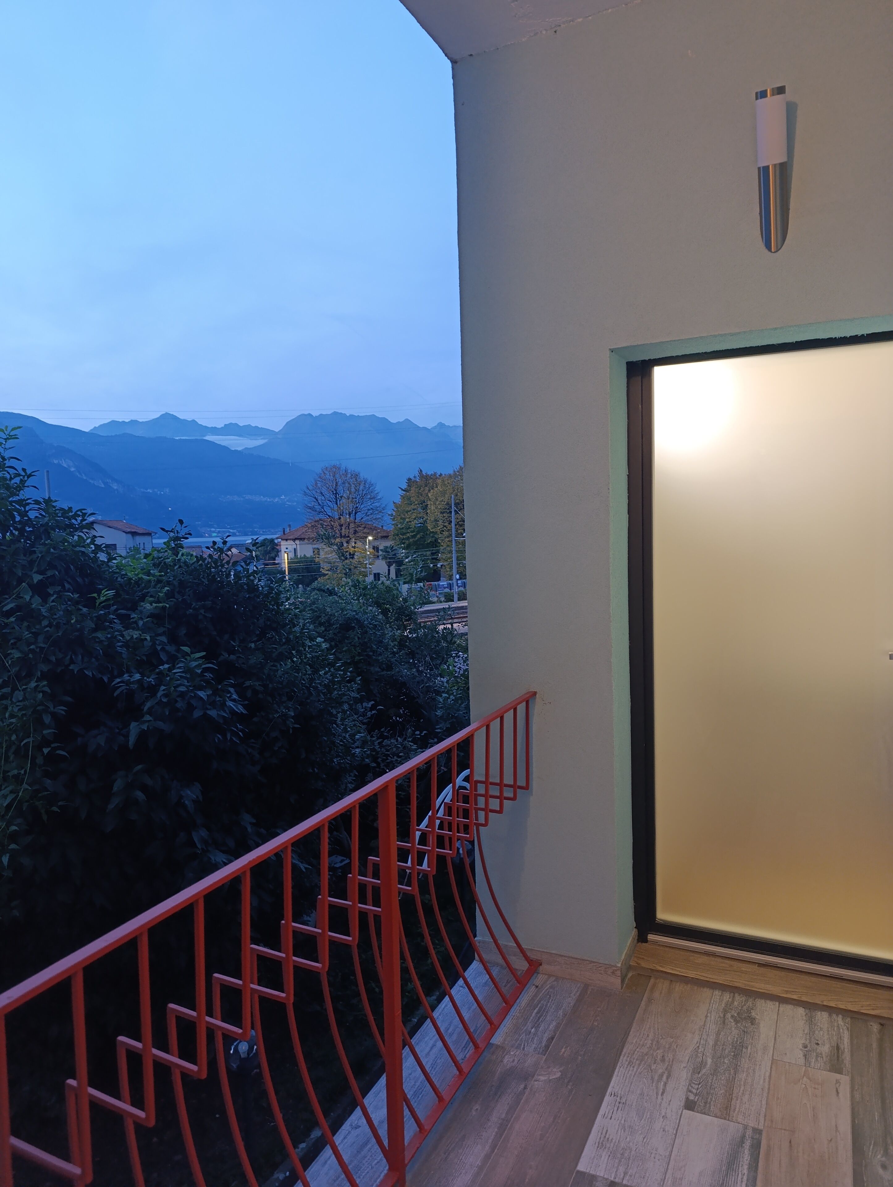 A balcony with a red railing overlooking a mountainous landscape.