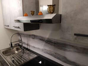 Uma cozinha moderna com uma pia de aço inoxidável, bancada de mármore e lava-louças embutida.