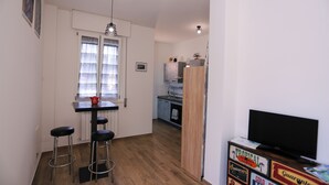 Eine kompakte Küche mit Essbereich, Barhocker, Fernseher und Kühlschrank.