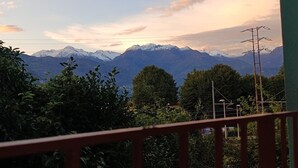 Eine Berglandschaft mit schneebedeckten Gipfeln, blauem Himmel und etwas Vegetation im Vordergrund.