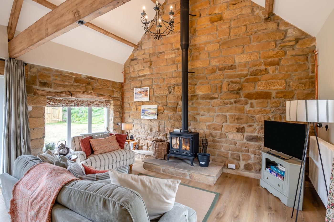 Ein gemütliches Wohnzimmer mit Steinwand, Kamin, Fernseher und einer bequemen Sitzecke.