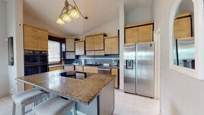 Una cocina moderna con encimeras de granito, electrodomésticos de acero inoxidable y armarios de madera.