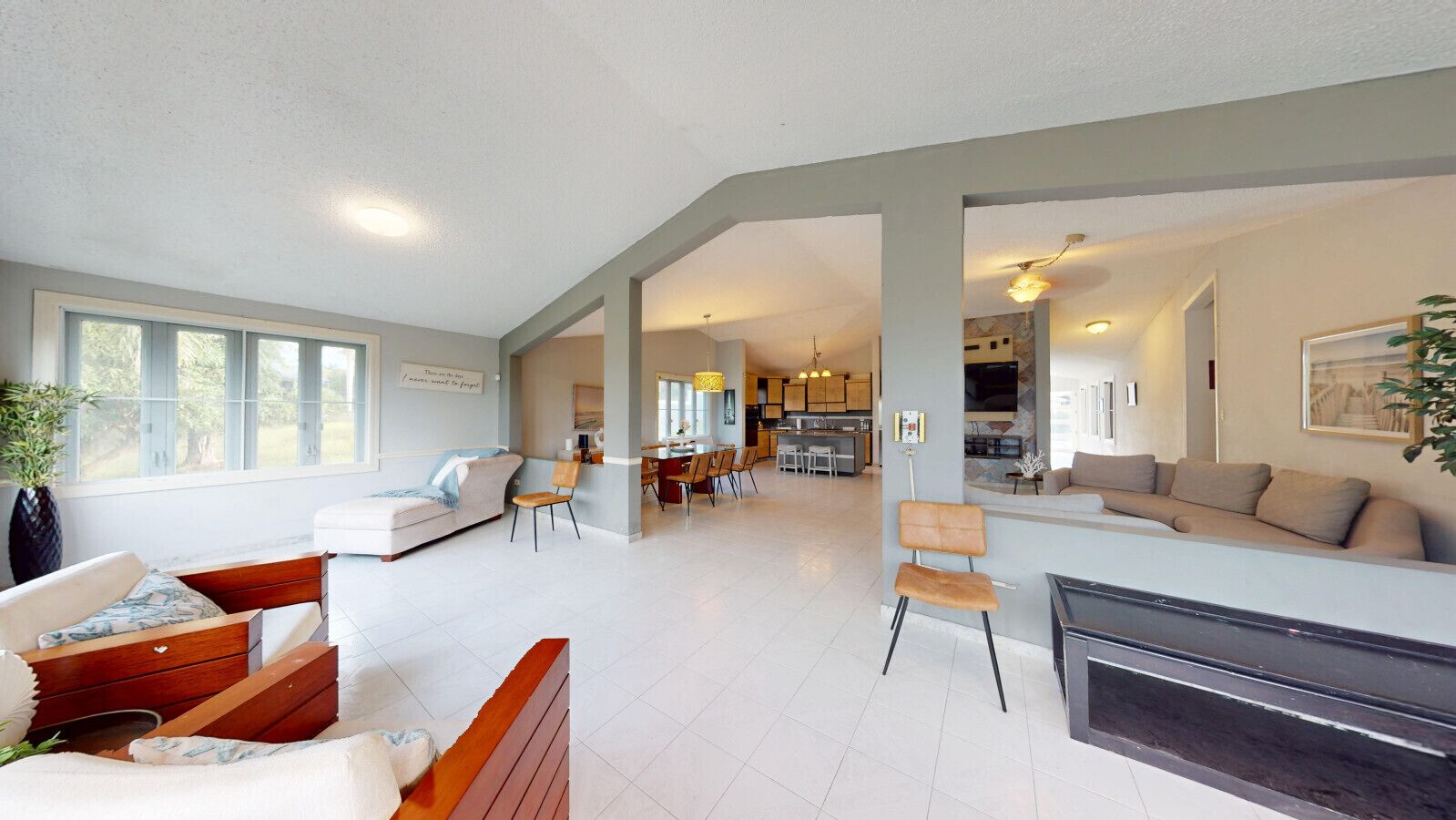 A spacious living area with a sofa, chairs, a dining table, and a kitchen in the background.