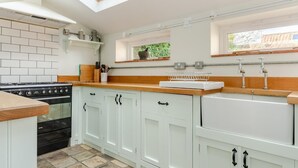 Een keuken met witte kasten, een zwarte kookplaat en een houten aanrecht, plus een dakraam.