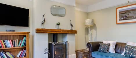 A living room with a fireplace, a bookshelf, a sofa, and a television.