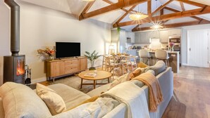 Een woonkamer met een bank, een televisie, een open haard en een eethoek met stoelen en een tafel.