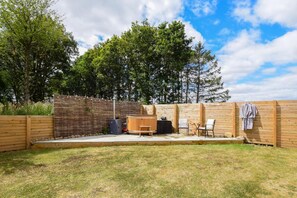 An outdoor patio area with a wooden fence, a hot tub, and seating. - 2 Bed in Market Harborough (oc-o34219) (Clipston)