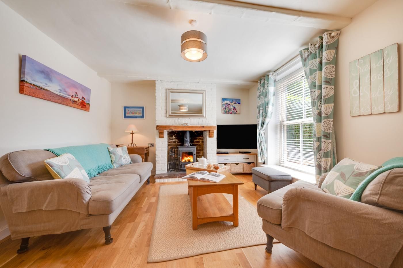 A cozy living room with two sofas, a fireplace, a television, and a window with curtains.