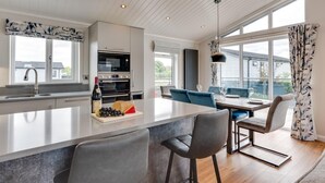 A modern kitchen with a central island, built-in appliances, and a dining area with a view. - 3 Bed in Burnham Market (oc-2334) (Burnham Market)