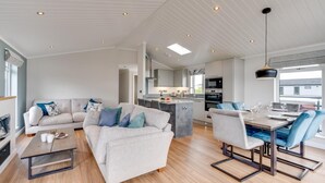A modern living room with a sofa, coffee table, and dining area. - 3 Bed in Burnham Market (oc-2334) (Burnham Market)