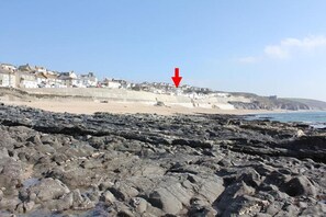 A rocky beach with houses in the background.